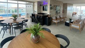 Un moderno vestíbulo de hotel con zona de bar, arreglos de asientos y grandes ventanales con vistas a la ciudad.