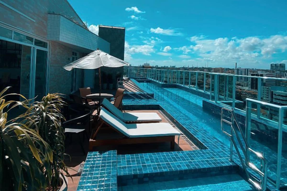 A rooftop pool area with lounge chairs and a potted plant.