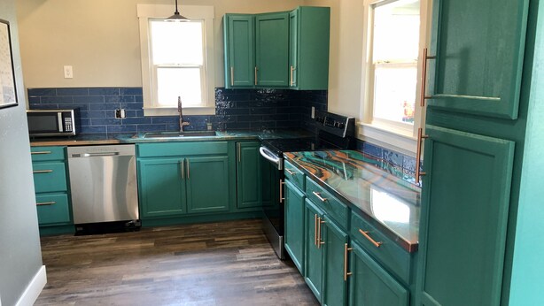 A kitchen with teal cabinets, a stainless steel dishwasher, and a black countertop. - Unique downtown Fruita apartment with bike storage! (Fruita)