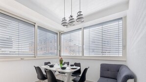 A modern dining area with a round table, black chairs, and a grey sofa. - Apartment Krempy - Two Bedroom Apartment with Terrace (Trogir)
