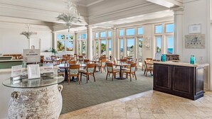 A spacious dining area with large windows, a central island, and a view of the ocean.