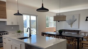 A modern kitchen with white cabinetry, a central island, stainless steel appliances, and pendant lighting. - Walk to the Beach. Elevator.   Heated Pool Spa open from Mar 1-Oct 31 (Cape May)