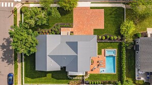 Eine Vogelperspektive eines Hauses mit Swimmingpool, überdachter Terrasse und gepflegtem Rasen.