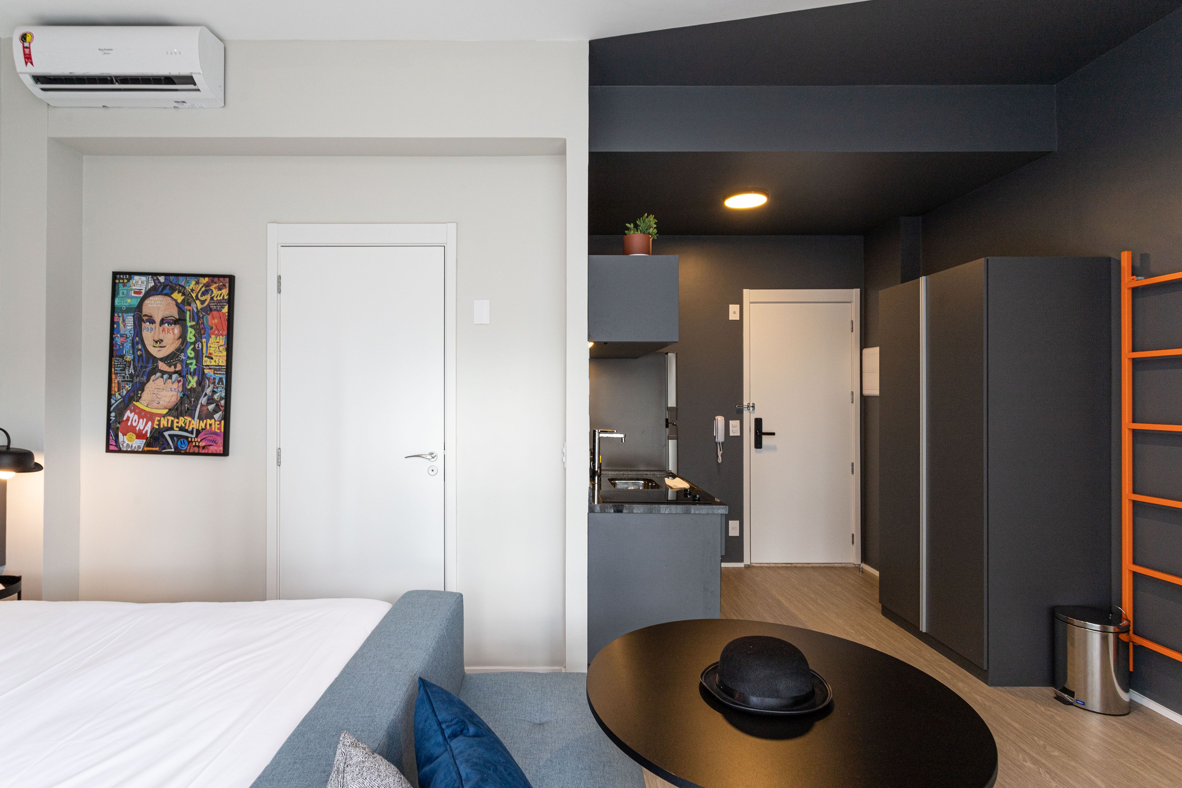 Una habitación de hotel moderna con cama, sofá, mesa de comedor y zona de cocina.