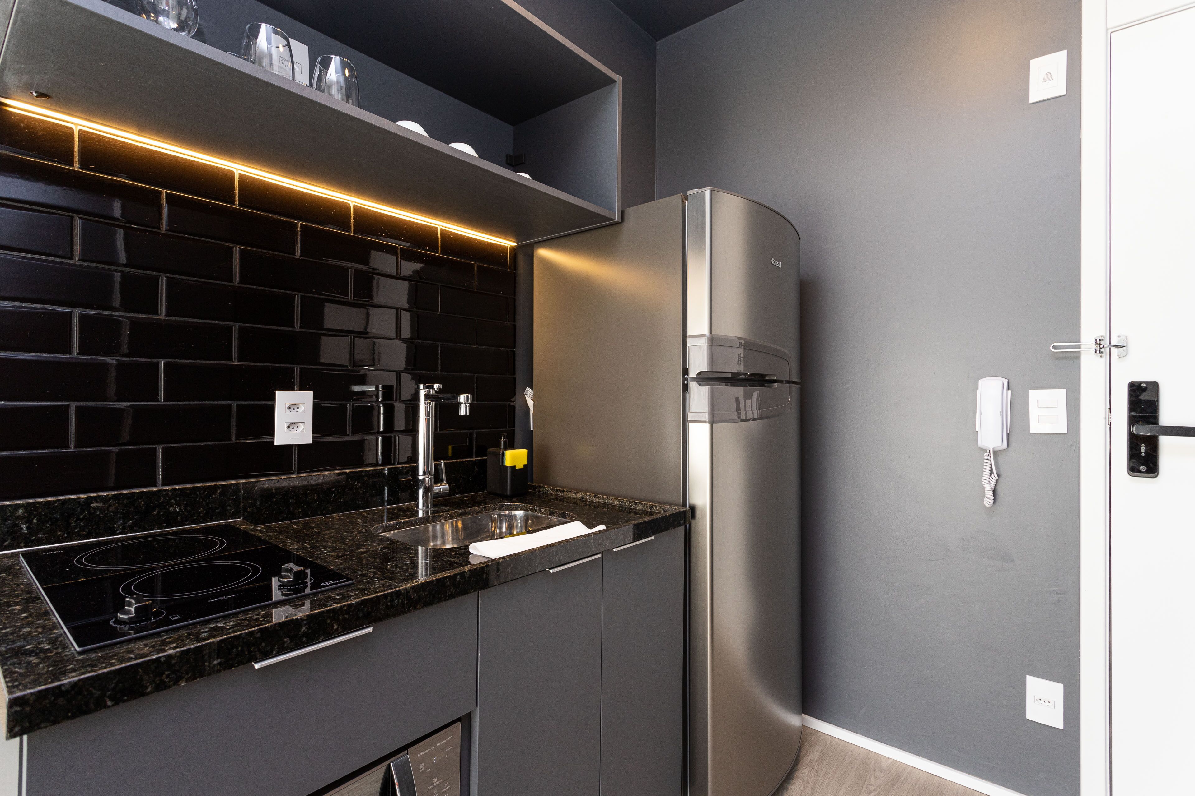 A modern kitchen with a black tiled backsplash, stainless steel appliances, and a built-in oven.