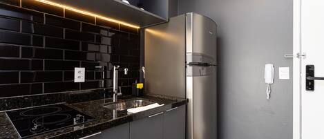 A modern kitchen with a black tiled backsplash, stainless steel appliances, and a built-in oven.