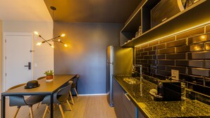 A modern kitchen with a black countertop, a refrigerator, and a dining area with a table and chairs.