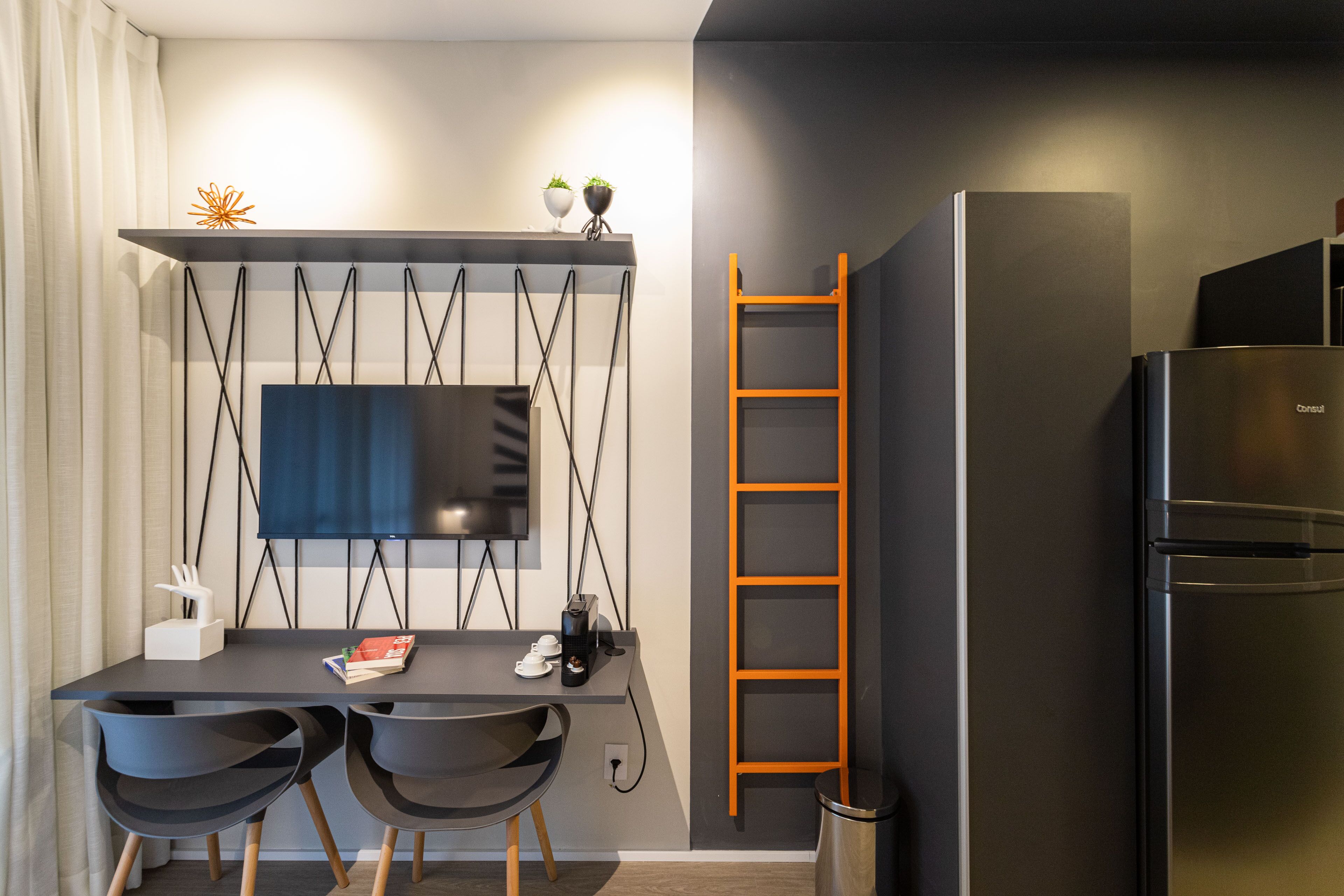 A modern kitchen with a built-in refrigerator, a black countertop, and a wall-mounted TV.