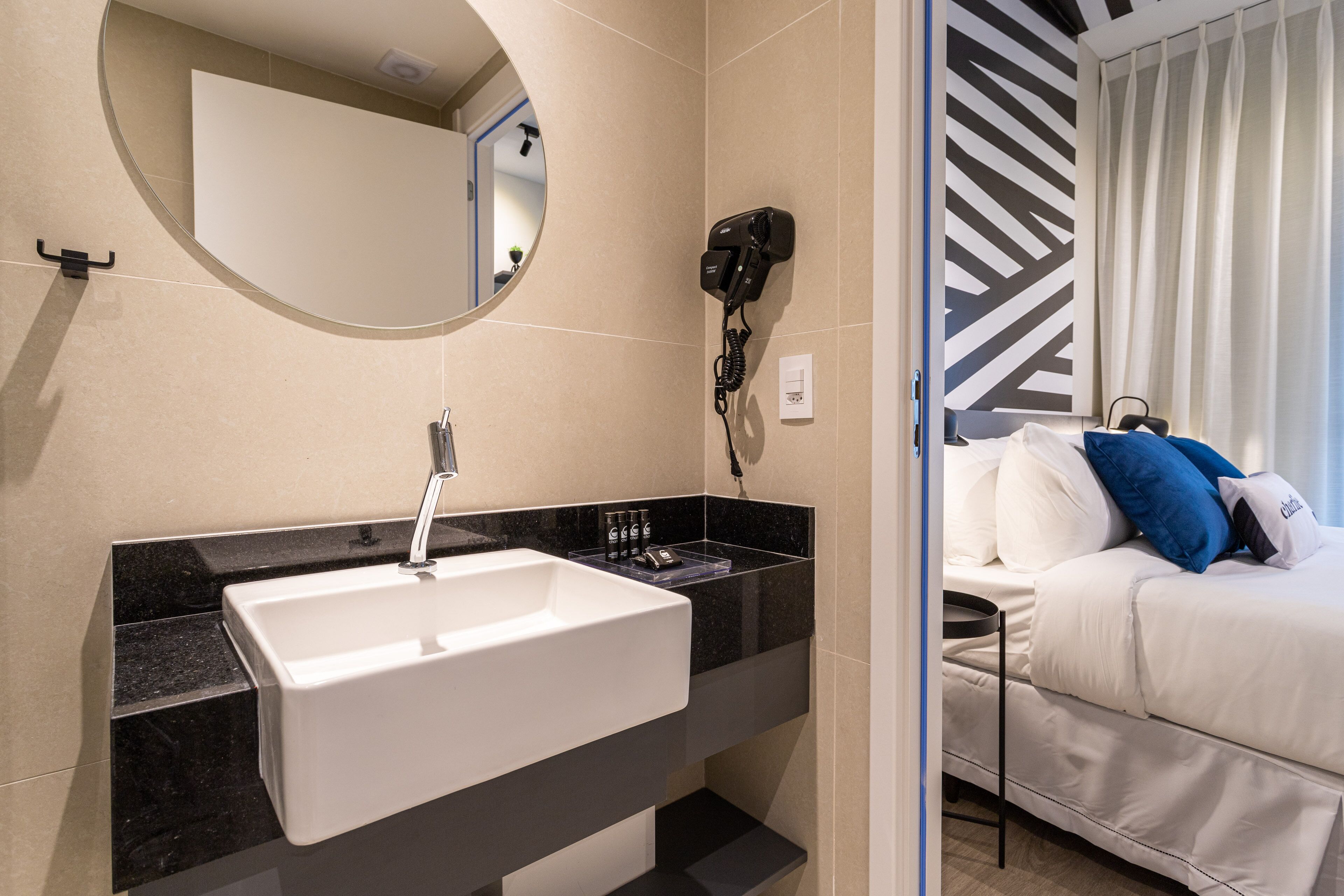 A modern bathroom with a white sink, a hairdryer, and a mirror.