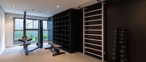 A modern gym with exercise equipment, a pull-up bar, and a rack of dumbbells.