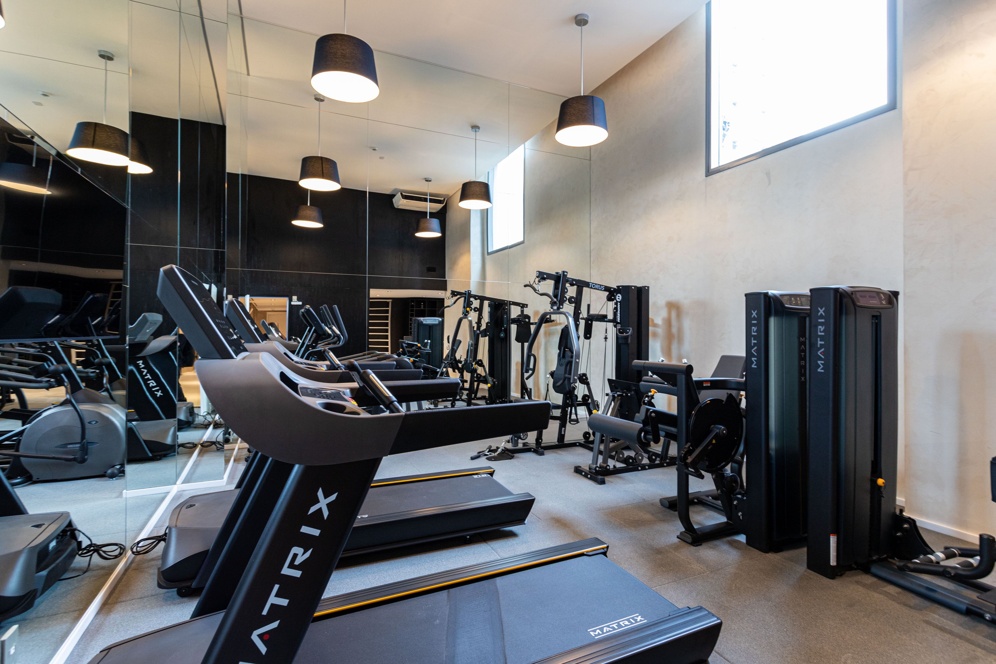 A modern gym with treadmills, weight machines, and mirrors.