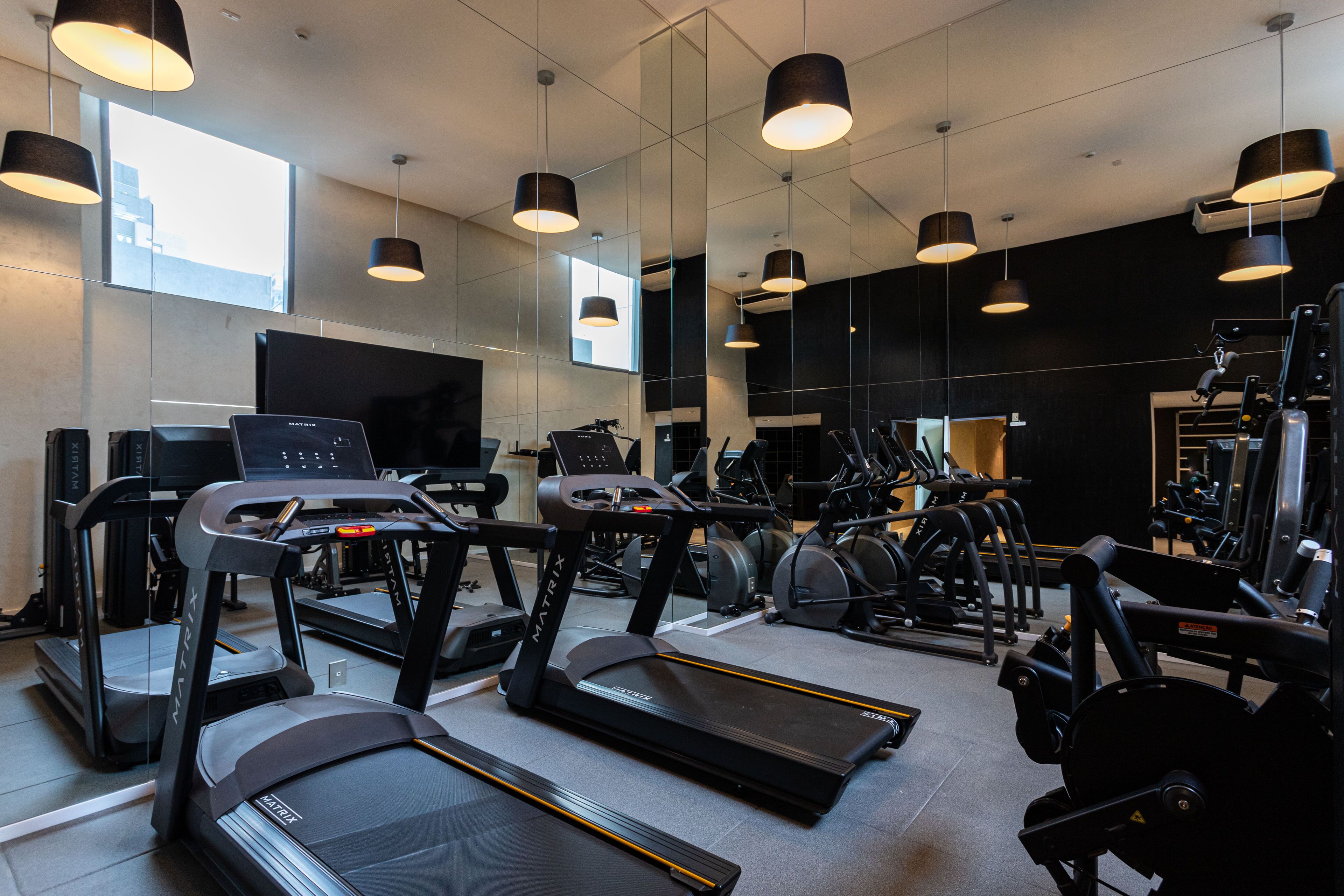 Un gimnasio con cintas de correr, bicicletas estáticas y máquinas de pesas.