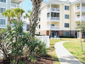 A multi-story hotel with balconies, a pathway, and landscaping.