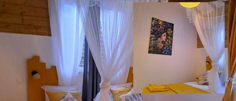 A bed with a canopy, a painting on the wall, and a yellow bedspread.