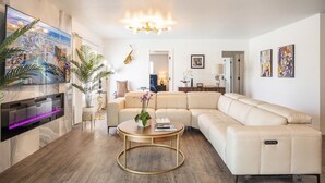 Ein modernes Wohnzimmer mit einer großen Eckcouch, einem runden Couchtisch und einem flachbildfernseher an der Wand.