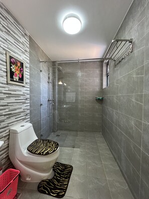 A modern bathroom with a toilet, shower, and a wall-mounted shelf. - Quinn Luxury Apartment, Kileleshwa (Nairobi)