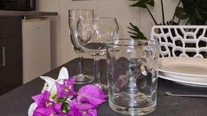 A dining table with wine glasses, a pitcher, and a flower arrangement. - Studio Ninirei (Papeete)