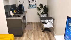 A compact living space with a kitchenette, a dining area, and a seating area with a yellow sofa. - Studio Ninirei (Papeete)