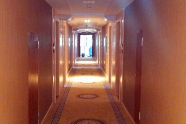 A hotel corridor with doors on both sides, a carpeted floor, and a light source at the end of the corridor. - Jin Zhou Hotel (Fengshan)
