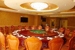 A conference room with a round table, chairs, and a chandelier.