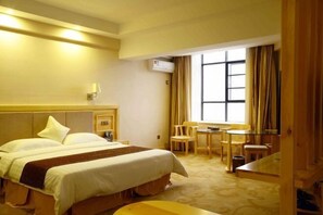 Ein Hotelzimmer mit Bett, Nachttisch, Lampe und einem Fenster mit Vorhängen.