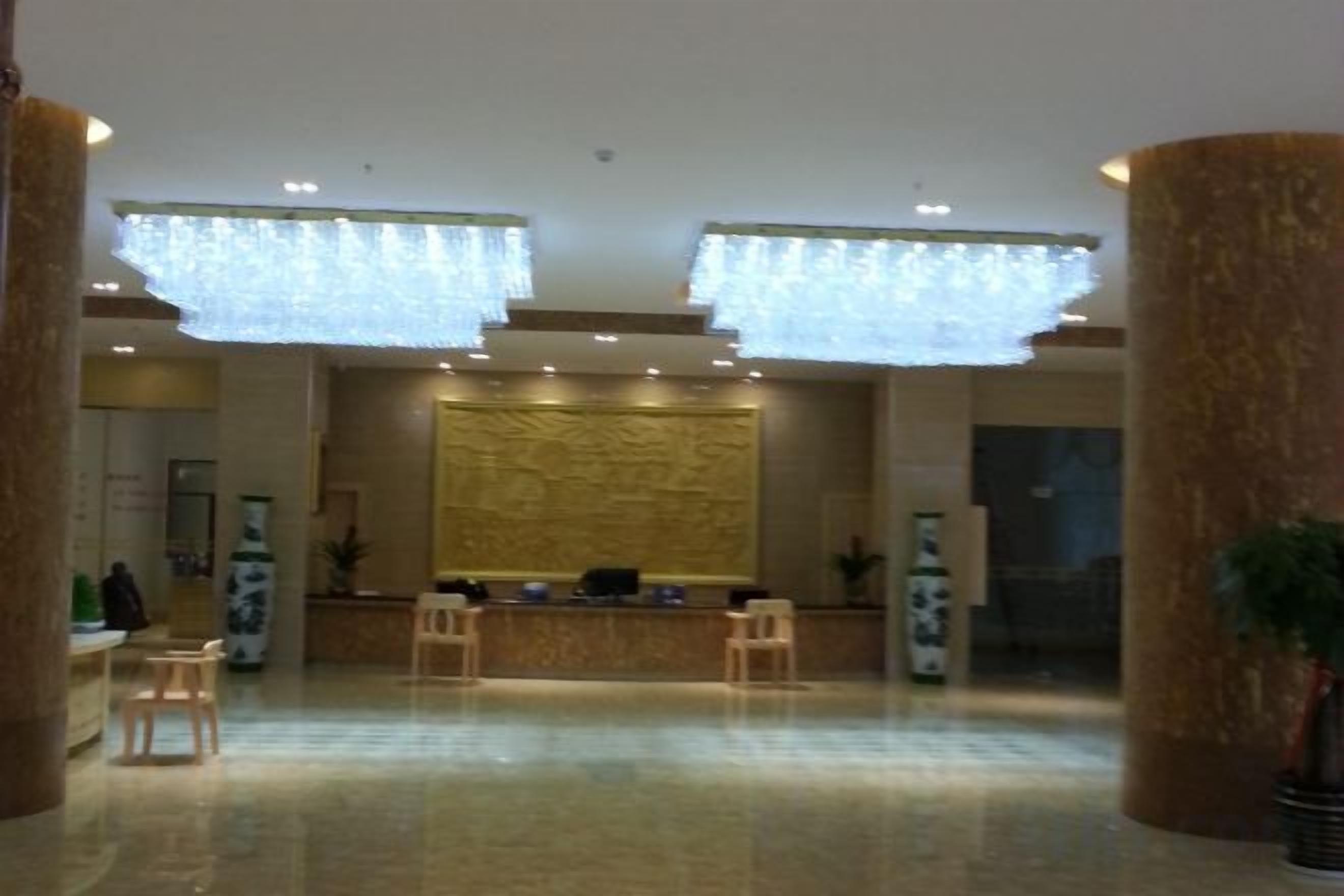 Un vestíbulo amplio con una mesa de recepción, dos zonas de estar y una gran pared decorativa.