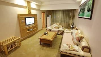 A living room with a television, sofa, coffee table, and a wooden bench.
