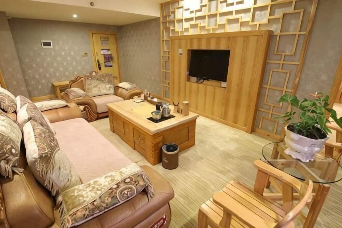 A living room with a sofa set, a coffee table, a TV, and a wooden wall panel.