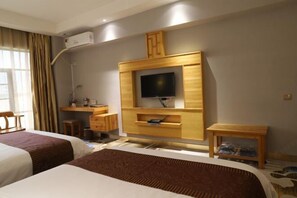 Ein Hotelzimmer mit zwei Betten, einem Fernseher, einem Schreibtisch und einem kleinen Tisch.