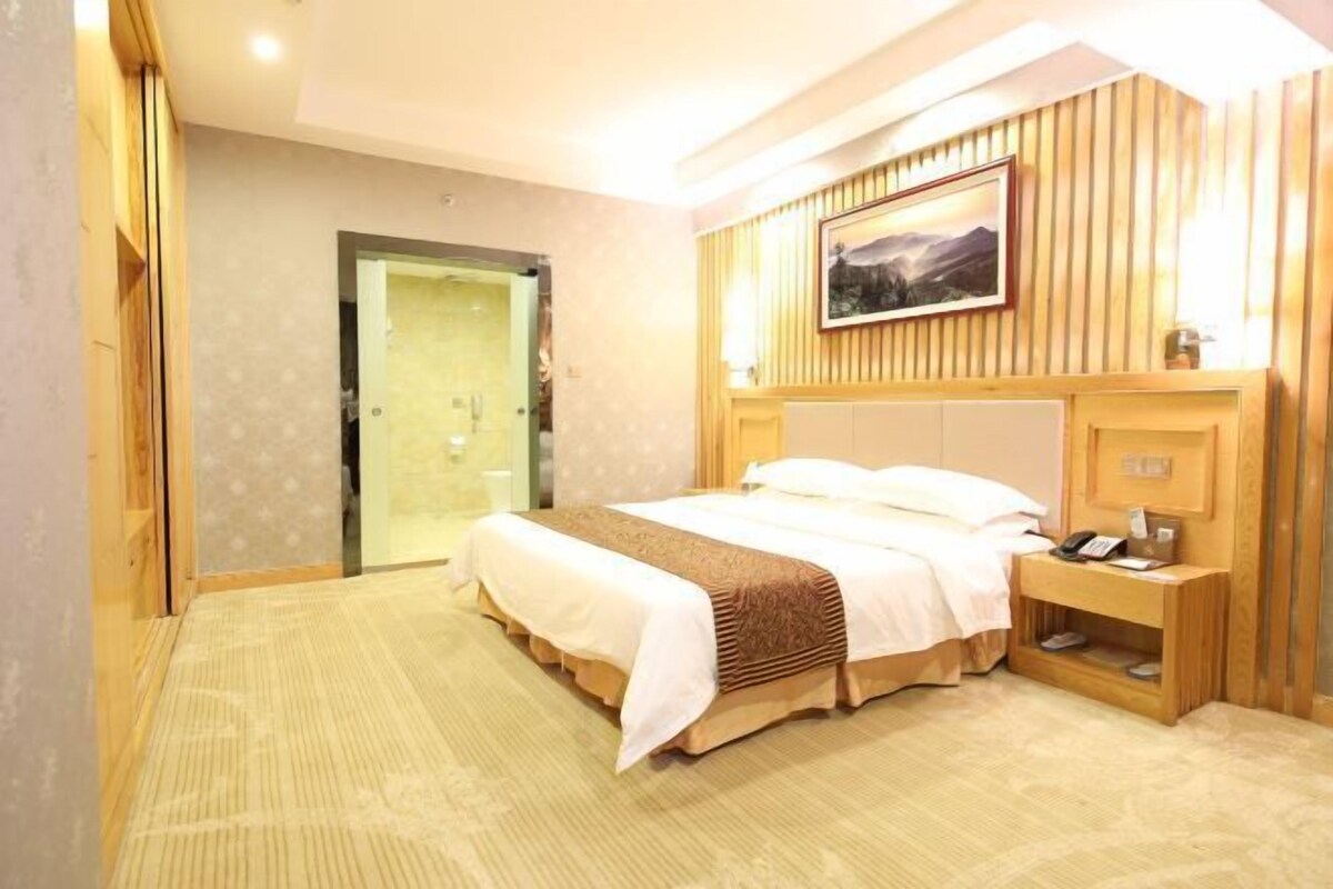 Ein Hotelzimmer mit Bett, Nachttisch und einem Bild an der Wand.