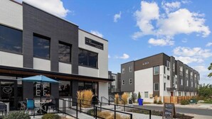 A modern building with a cafe area featuring outdoor seating and a signboard.