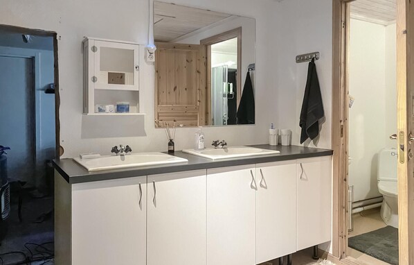 Un baño con dos lavabos, un espejo y un inodoro.