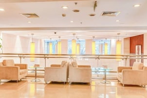A modern lobby with a glass railing, seating area, and a view of the outdoors.