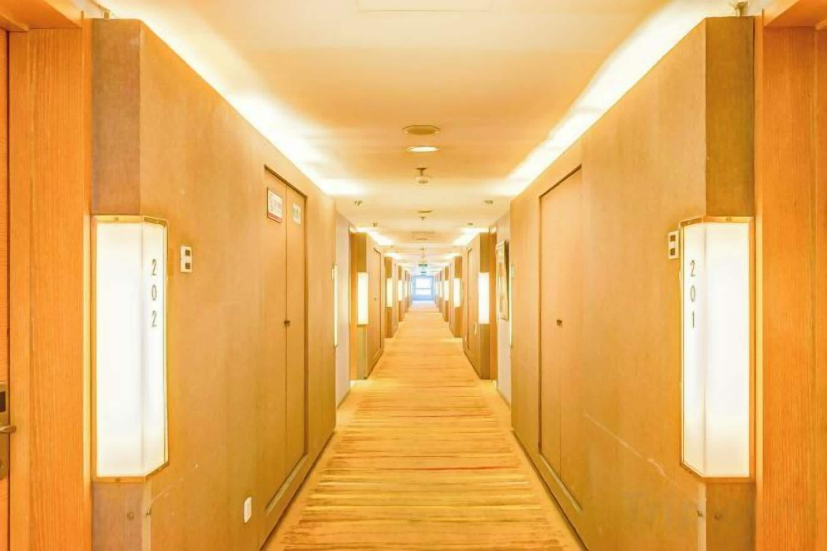 A hotel hallway with doors numbered 202 and 201, wooden walls, and a carpeted floor.
