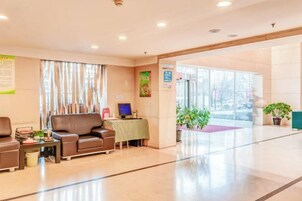 Un vestíbulo de hotel con una recepción, zona de estar y un ventanal grande.