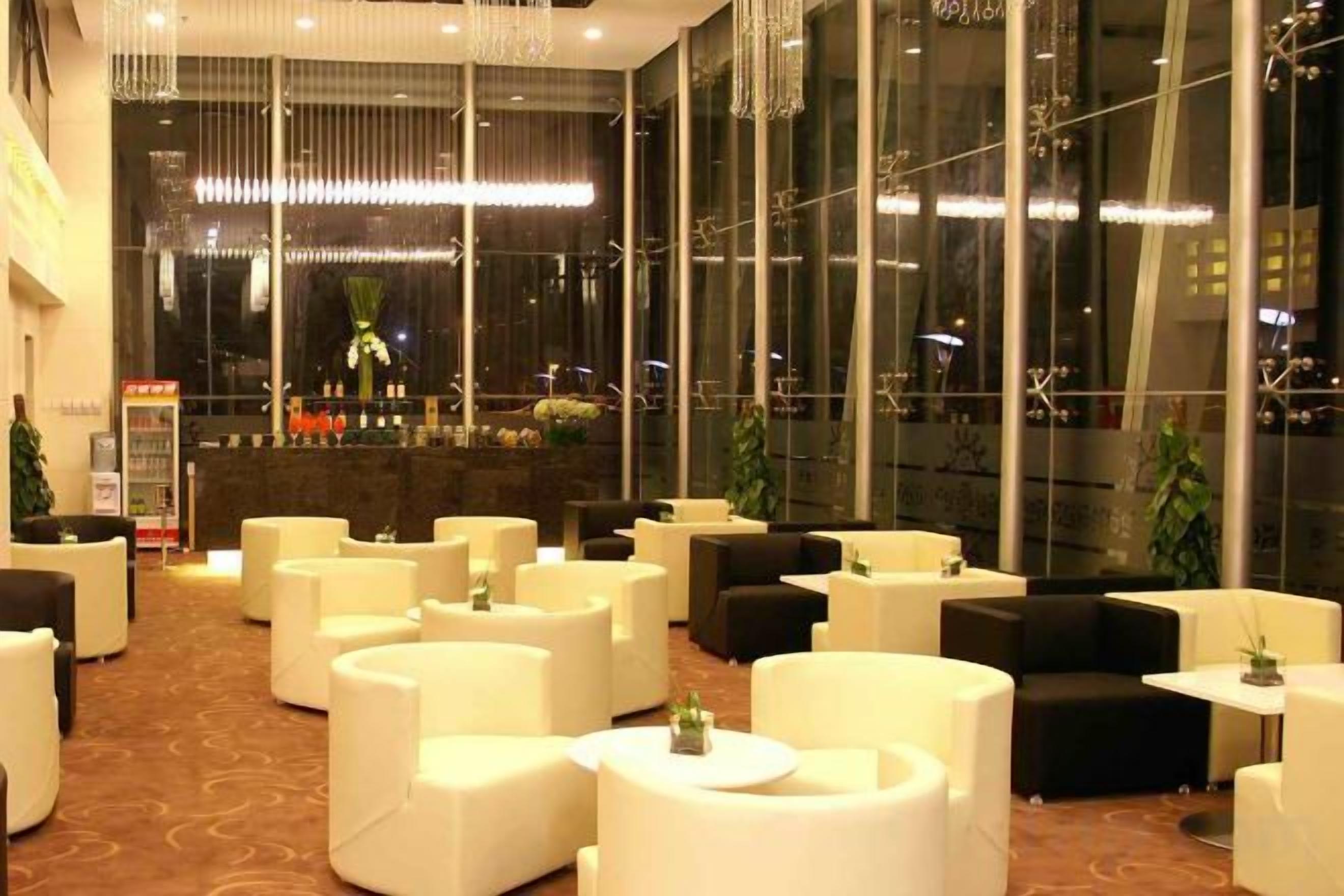 A hotel lobby with multiple seating areas, a reception desk, and large windows.