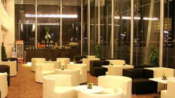 A hotel lobby with multiple seating areas, a reception desk, and large windows.