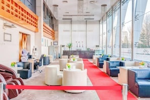 A hotel lobby with a red carpet, seating areas, a reception desk, and large windows. - Qiangang Hotel (Qian'an)