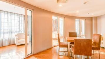 Une pièce moderne avec un plancher en bois, une table à manger avec des chaises et une grande fenêtre.