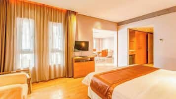 Une chambre d’hôtel avec un grand lit, un bureau avec un ordinateur, une télévision et une vue sur le couloir.