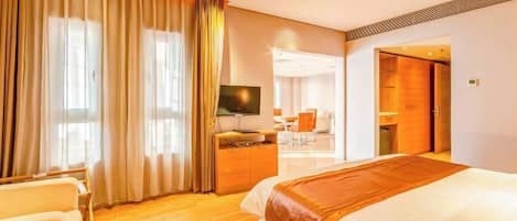 Habitación de hotel con una cama grande, un escritorio con una computadora, un televisor y vista al pasillo.