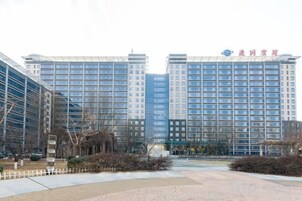 Un hotel de varios pisos con una fachada moderna, un patio central y un cielo despejado.