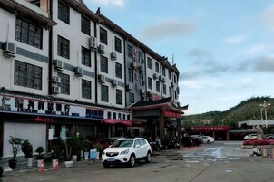 Un edificio de varios pisos con estilo arquitectónico tradicional, con una fila de tiendas en la planta baja y un estacionamiento al frente.