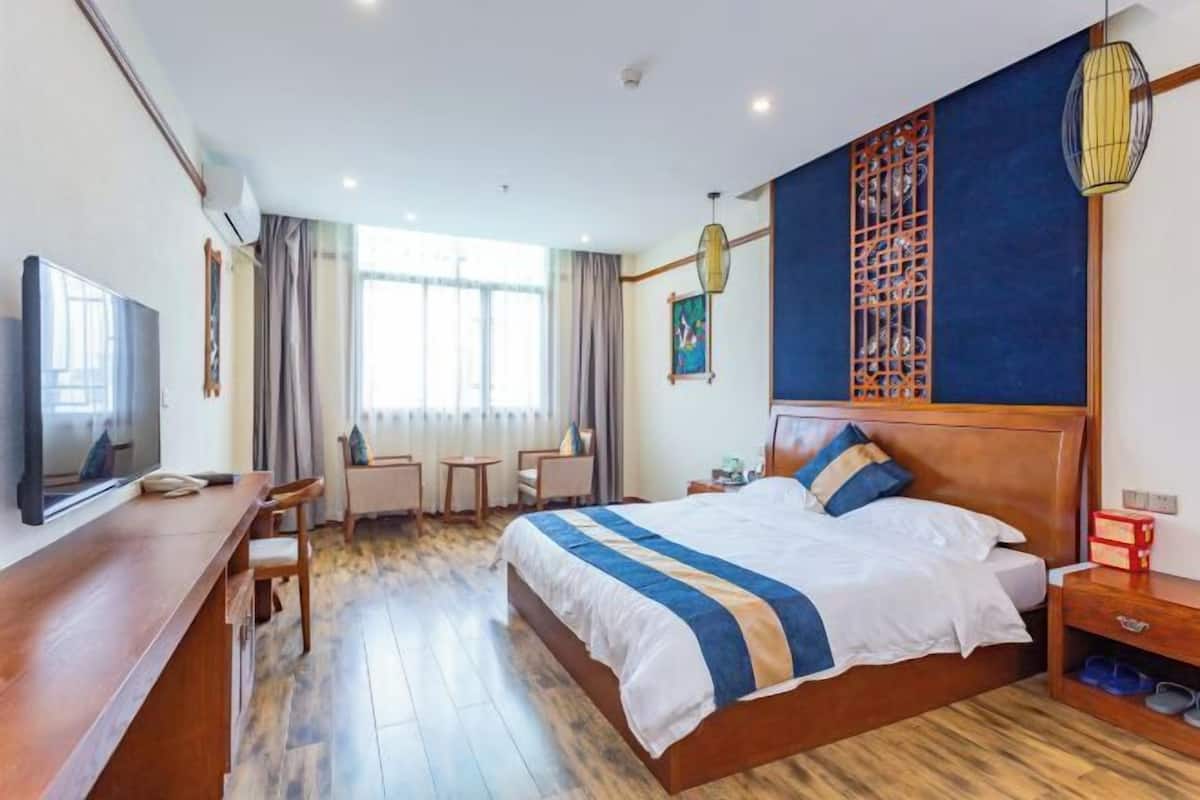 A hotel room with a bed, a desk, a TV, and a window with curtains.