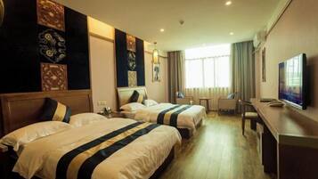 A hotel room with two beds, a desk, a television, and decorative wall panels.