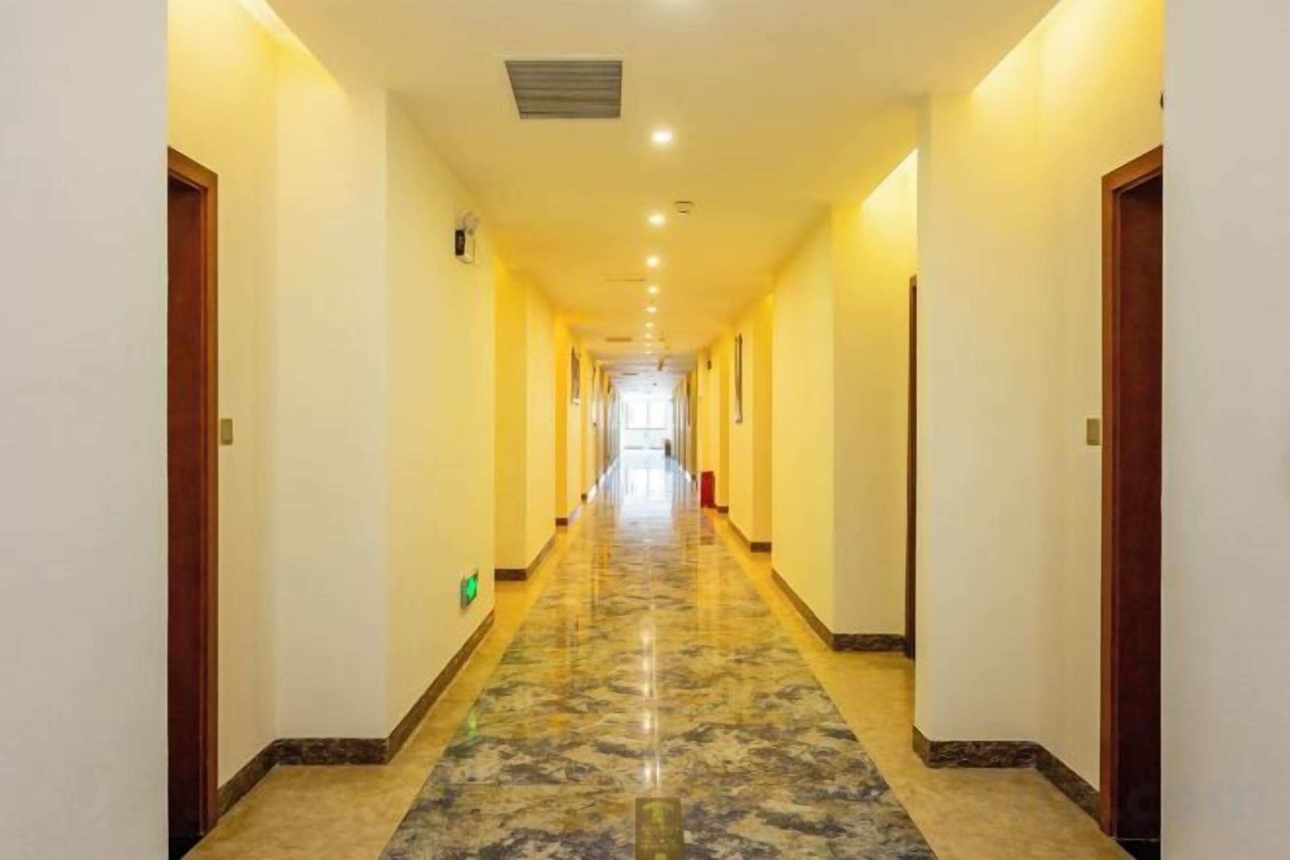 A long, narrow hallway with a marble floor and doors on both sides.