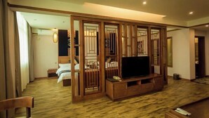 Une chambre d’hôtel équipée d’un meuble de rangement en bois, d’un lit et d’un téléviseur.