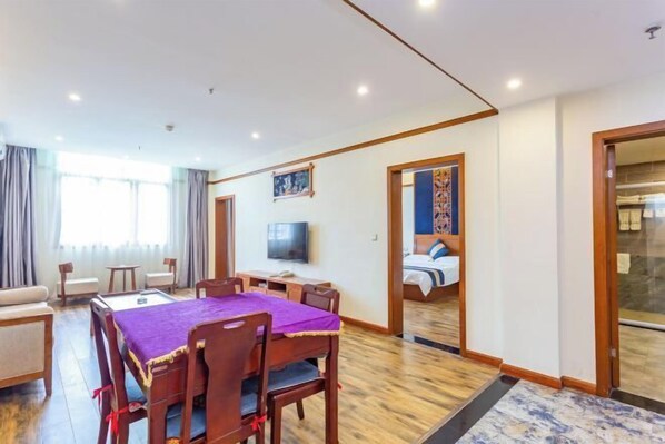 A hotel room with a dining area, a TV, a bed, and a view of the outside. - Hongzhi Hotel (Xingren)