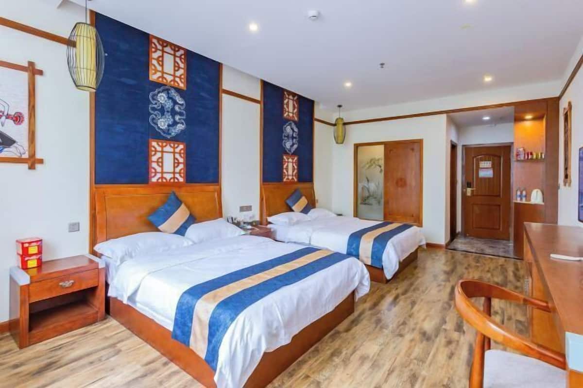 A hotel room with two beds, wooden headboards, and a wooden floor.