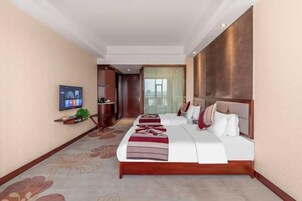 Habitación de hotel con una cama grande, un televisor en la pared y vistas al exterior.